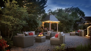A patio area with wicker furniture, a gazebo, and a brick floor. - Inn on Randolph (Napa)