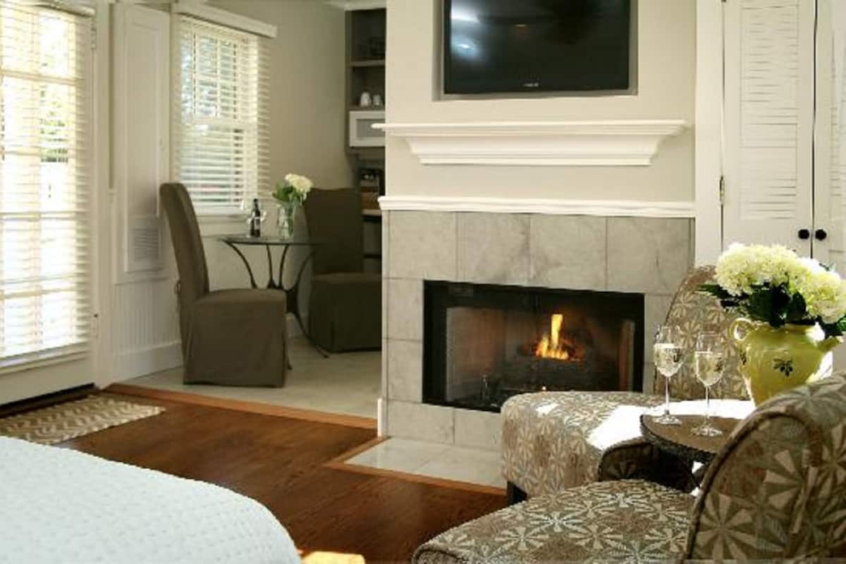 A living room with a fireplace, a television mounted above it, and a dining area with a table and chairs.