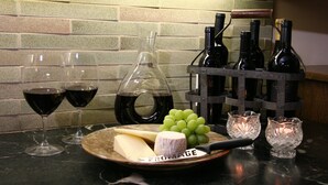 Une table de dégustation de vin avec des verres à vin, une bouteille de vin, du fromage, des raisins et un couteau à fromage, le tout disposé sur un comptoir en marbre.