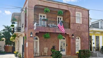Traditional building with a balcony and American flag, situated on a street corner.
