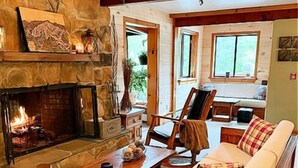 Una sala de estar acogedora con chimenea, muebles de madera y una pared de piedra.