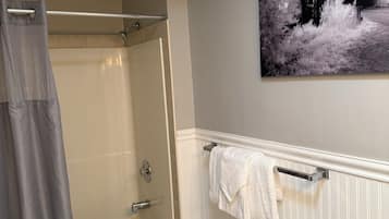 A bathroom with a shower, a towel rack, and a wall-mounted picture.