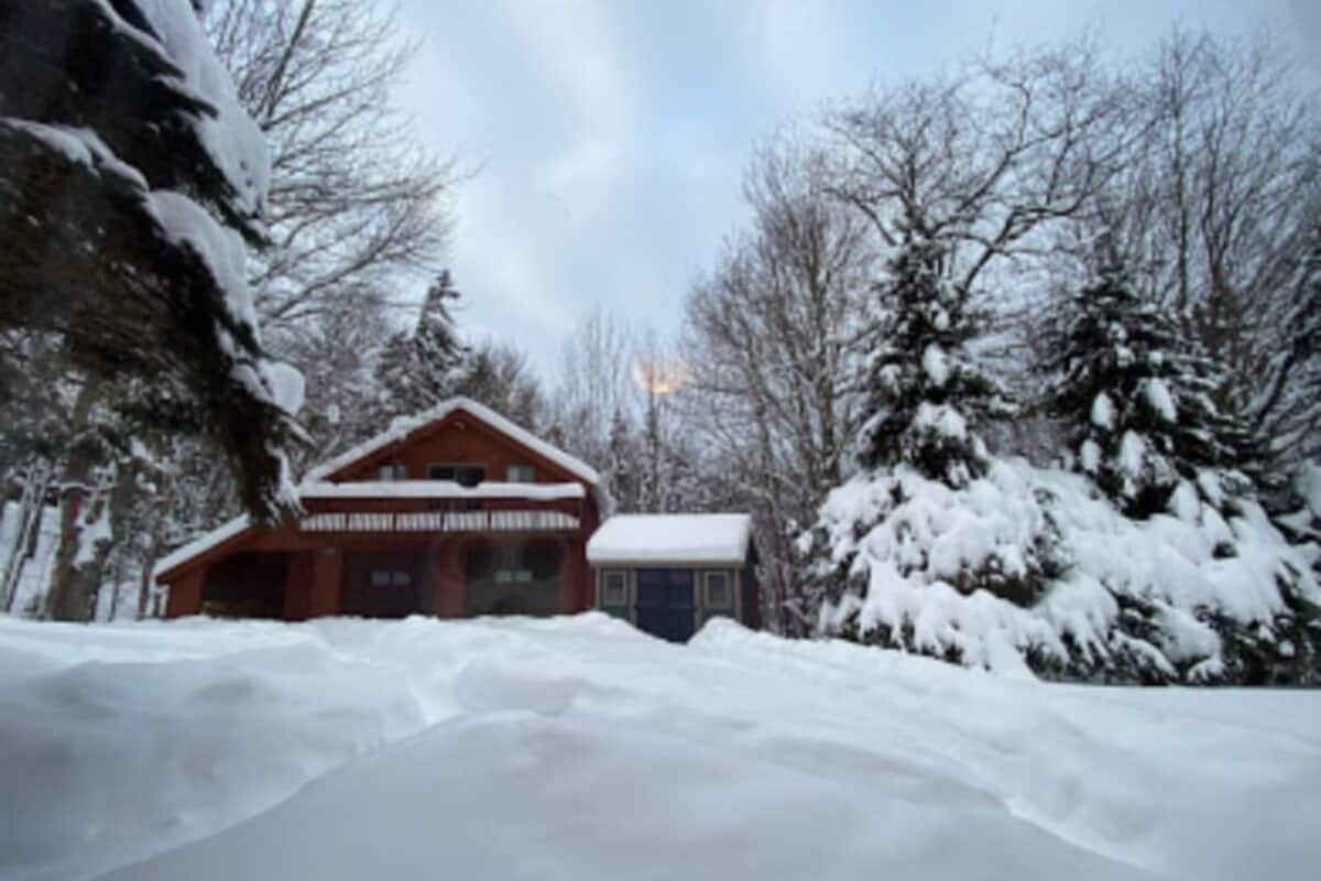 A lodge with a red exterior and a snow-covered roof, surrounded by trees and a snowy landscape.