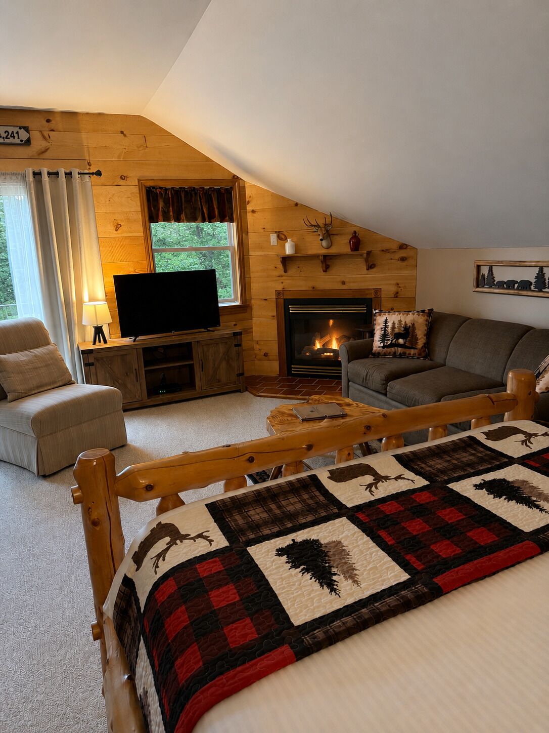 Een gezellig cabin interieur met een open haard, een televisie, een bank en een bed met quilt.