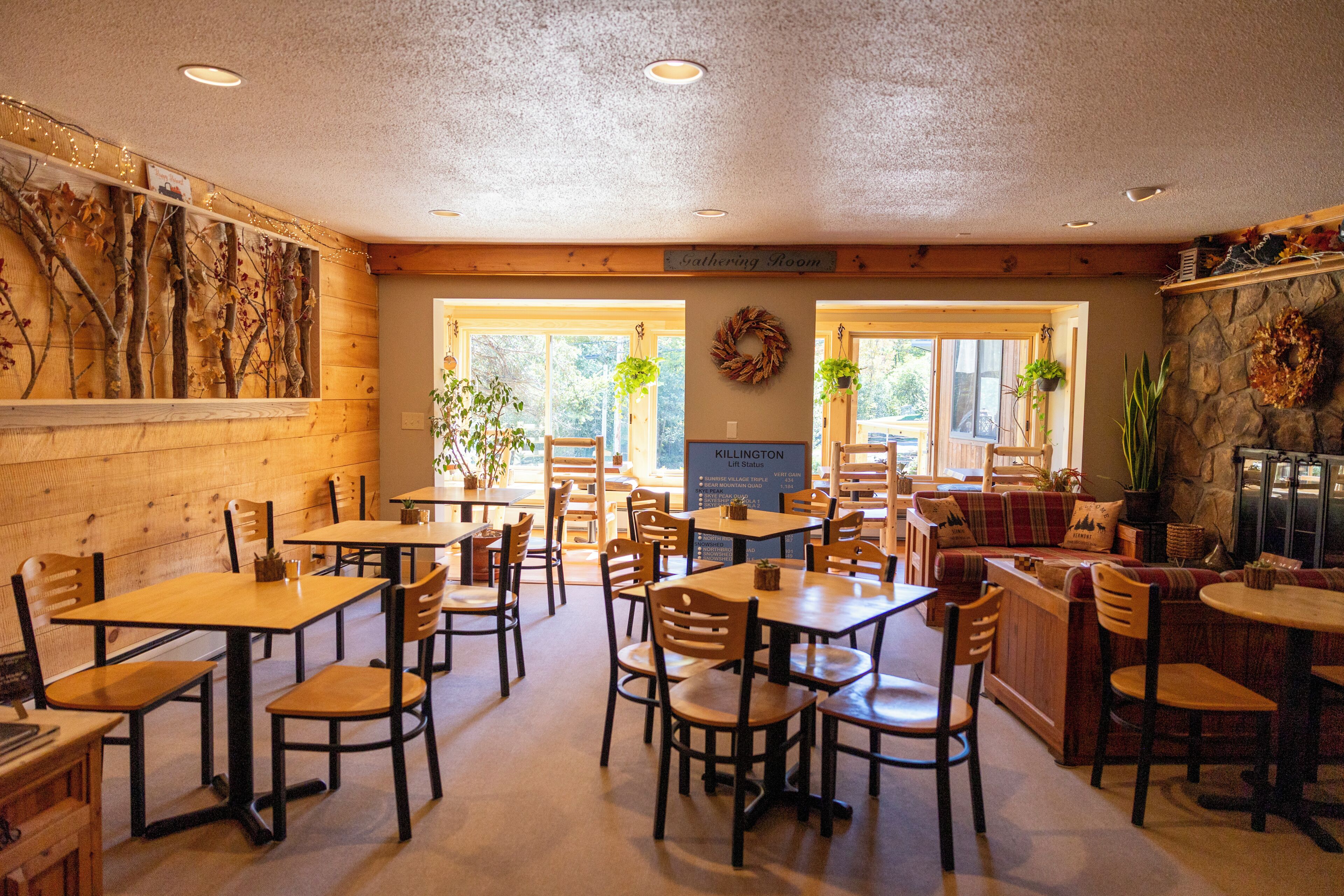 Un restaurante con mesas y sillas de madera, pared de piedra y un letrero que dice 'Killington'.