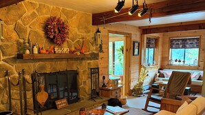 Un acogedor interior de cabaña con chimenea de piedra, muebles de madera y pared de piedra.