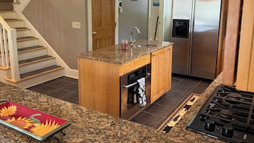 A kitchen with granite countertops, a built-in oven, a stainless steel refrigerator, and a wooden island.