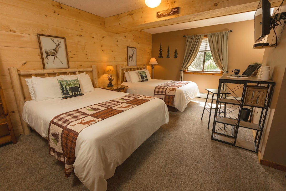 A cozy room with two beds, a desk, and a chair.
