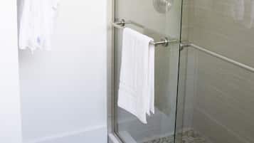 A glass-enclosed shower with a white towel hanging on the door handle.