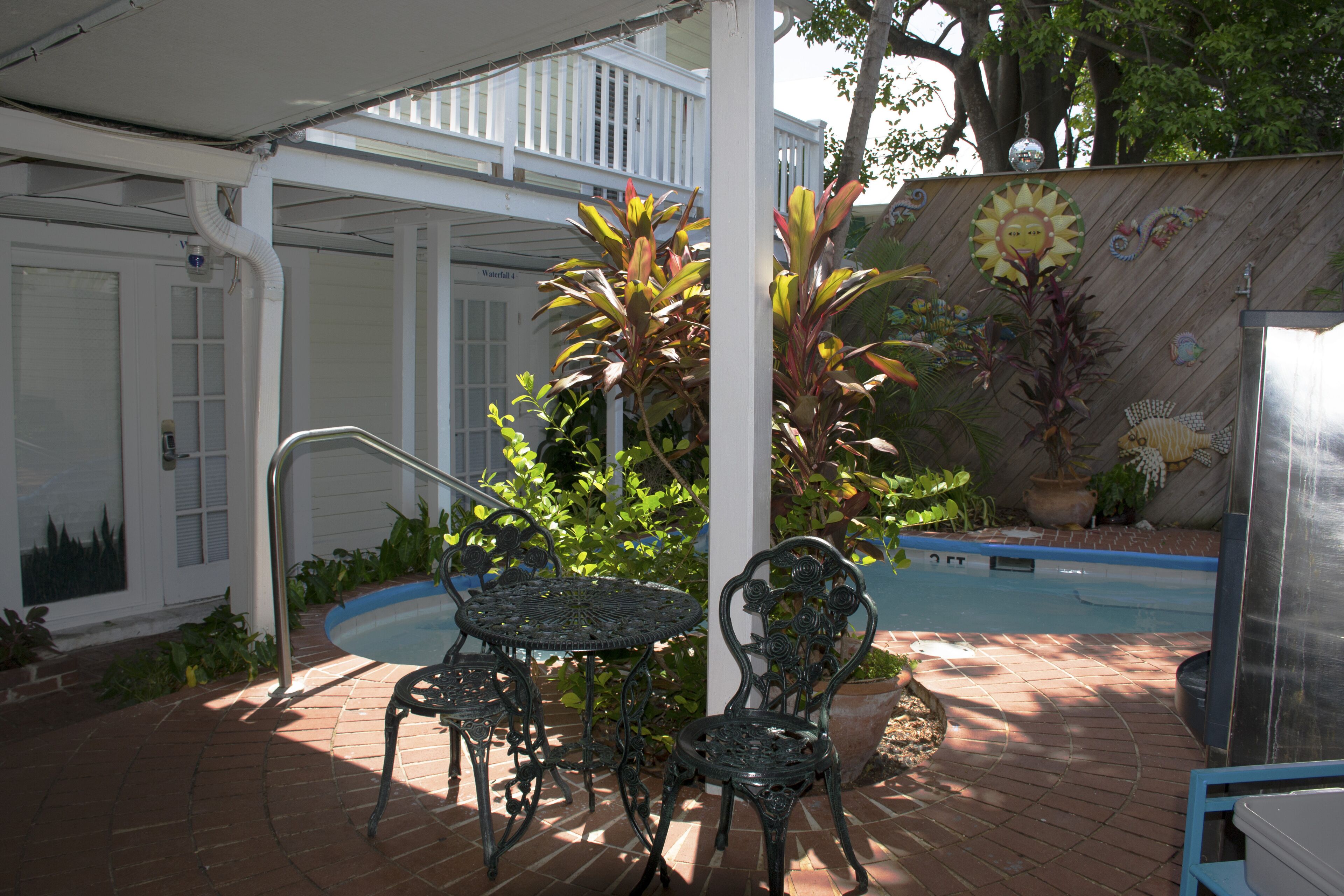 Eine Terrassenanlage mit Pool, Metallstühlen und einer Topfpflanze.