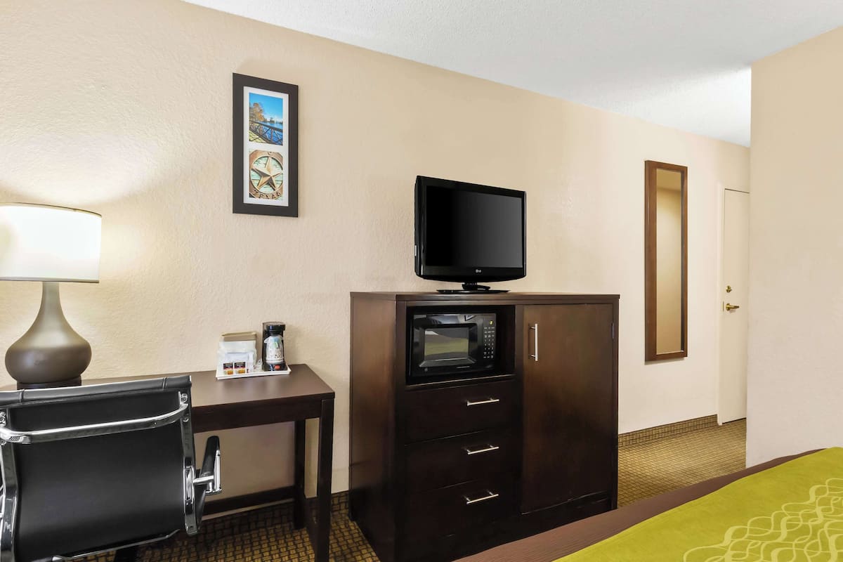 Une chambre d’hôtel équipée d’un bureau, d’une télévision, d’un four à micro-ondes, d’une machine à café et d’un lit.