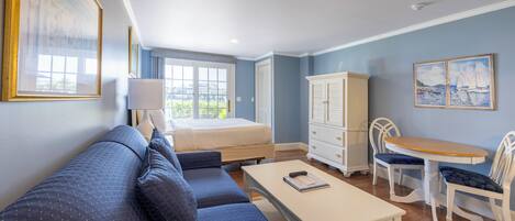 A bedroom with a bed, a sofa, a desk, and a dining area with chairs.
