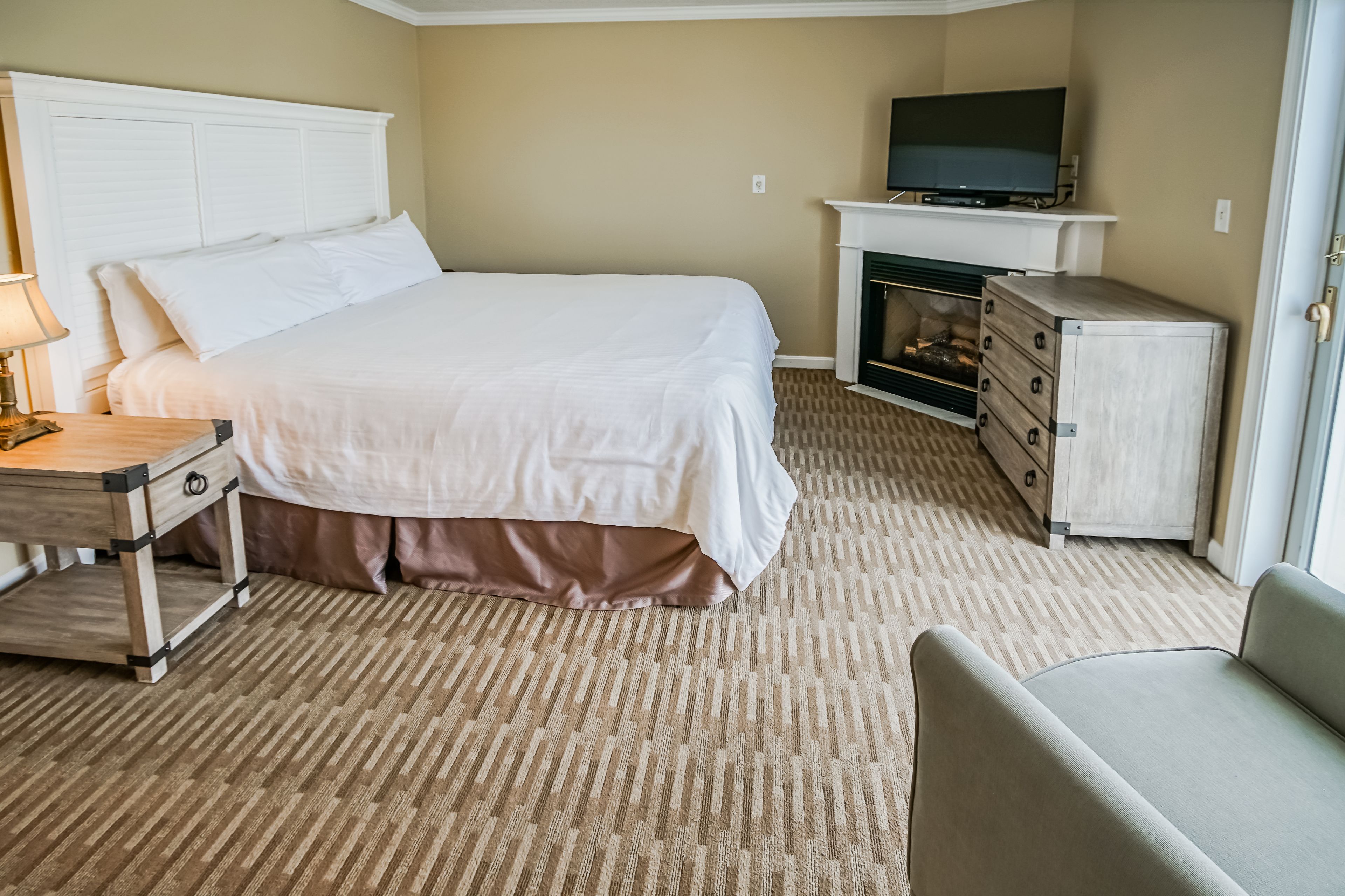 Een hotelkamer met een groot bed, een televisie, een open haard en een bureau met een lamp.