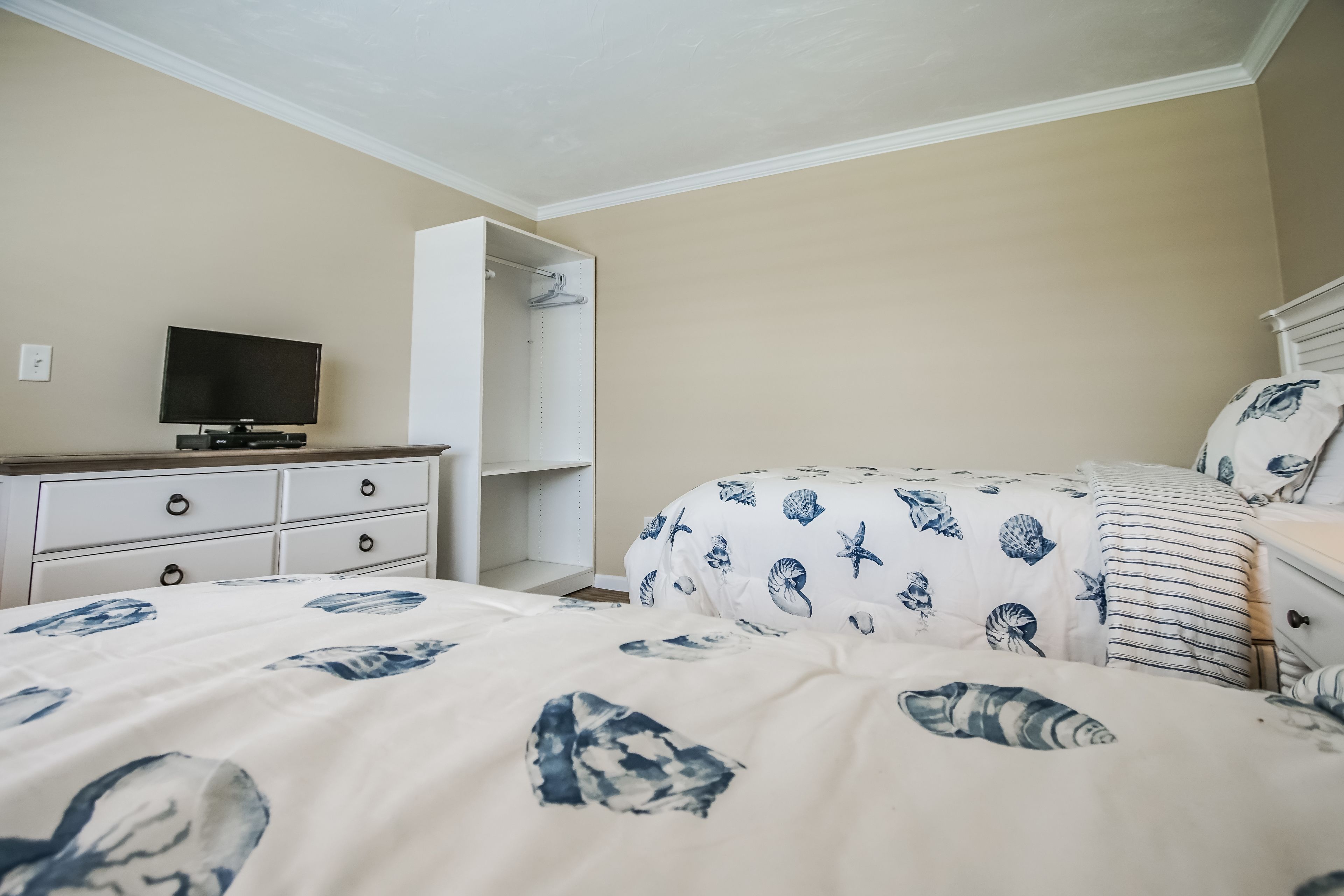 A bedroom with a bed, a TV, a wardrobe, and a closet.