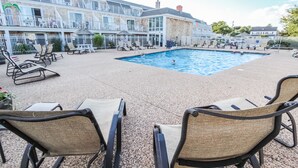 Zona de piscina con sillas de descanso y un edificio con varios balcones.