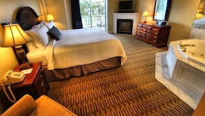 Habitación de hotel con una cama grande, zona de estar, chimenea, televisor y baño con bañera.
