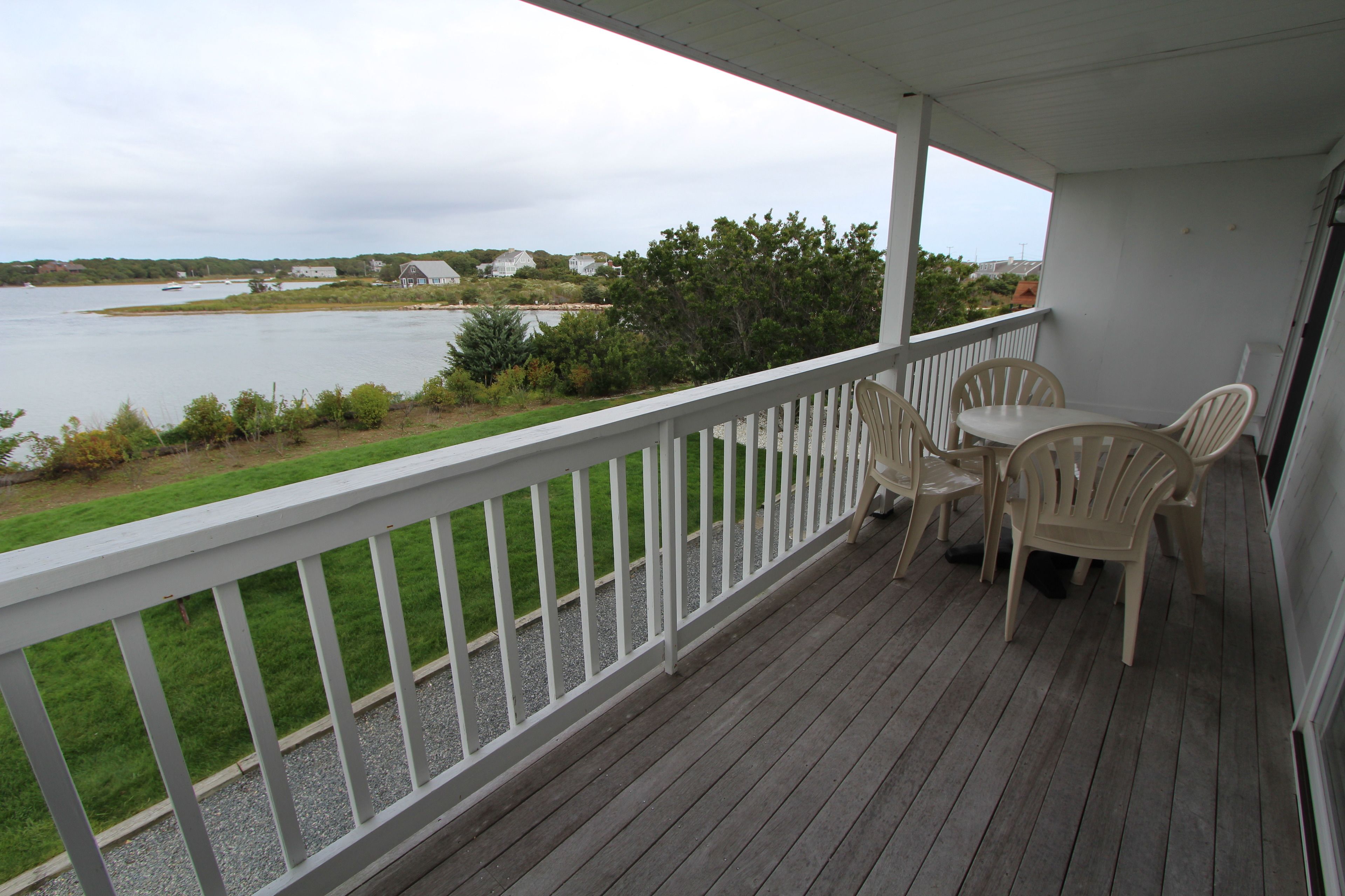 A covered porch with a view of a lake, featuring a table and chairs.