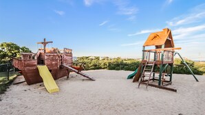 A sandy beach with two wooden play structures, one with a slide and the other with a ladder. - InnSeason Resorts Surfside (East Falmouth)