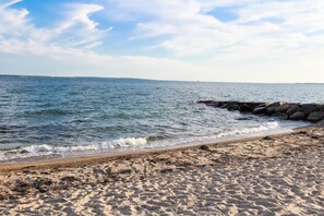 A sandy beach with a rocky breakwater and calm sea. - InnSeason Resorts Surfside (East Falmouth)