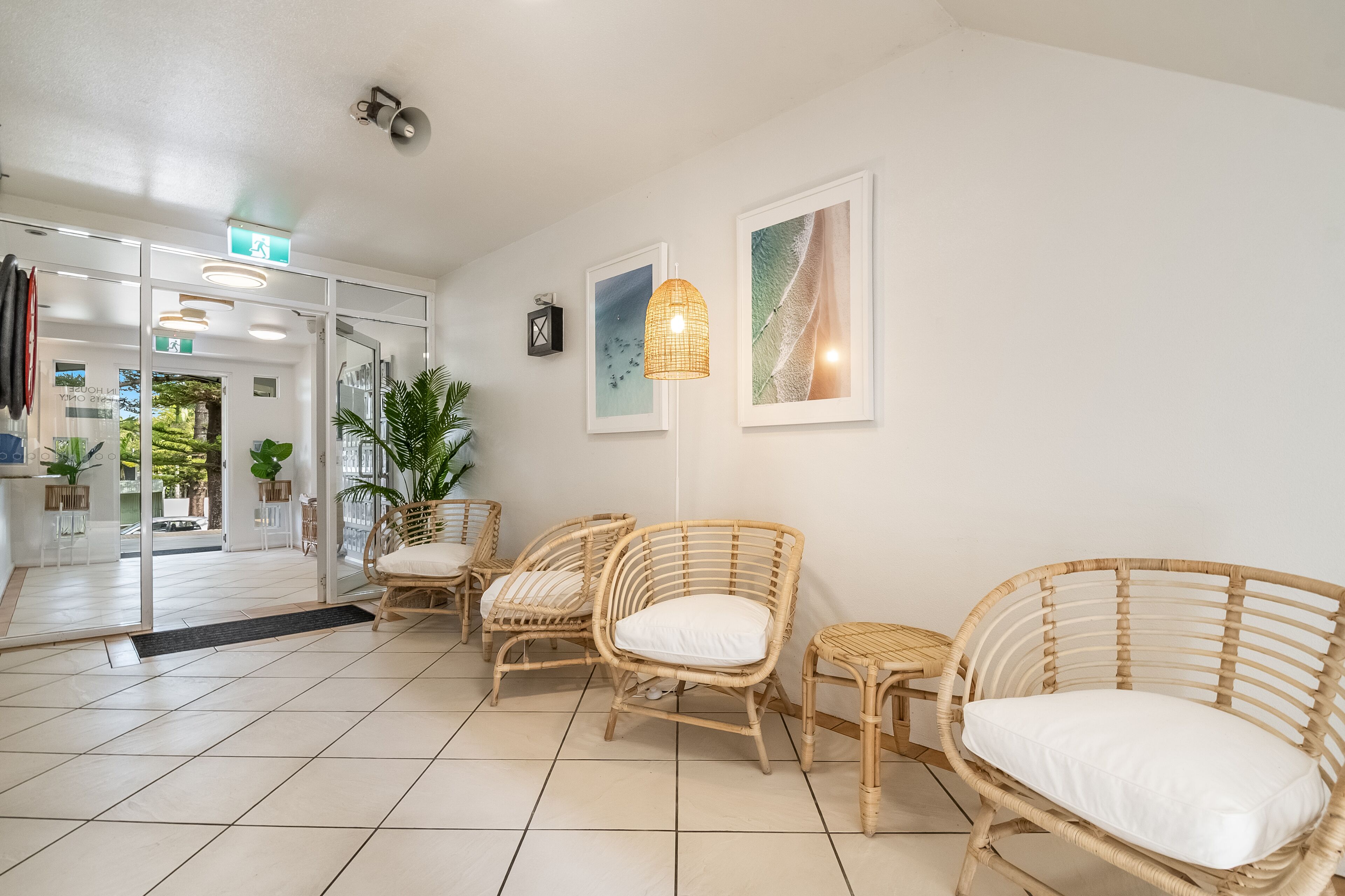 A reception area with wicker chairs, a floor lamp, and framed artwork on the wall.