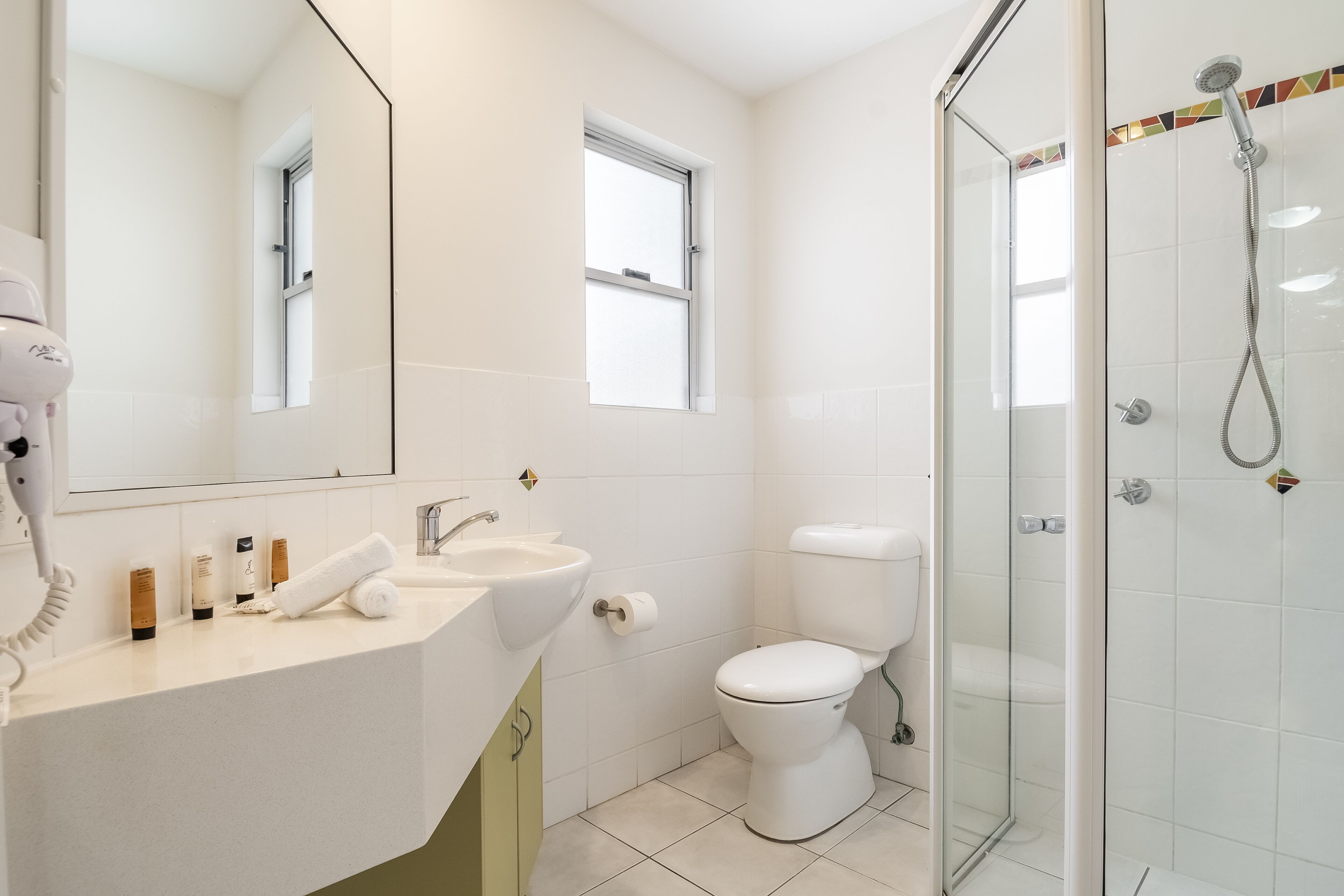 Une salle de bain moderne avec une douche à parois de verre, un lavabo blanc et des toilettes.