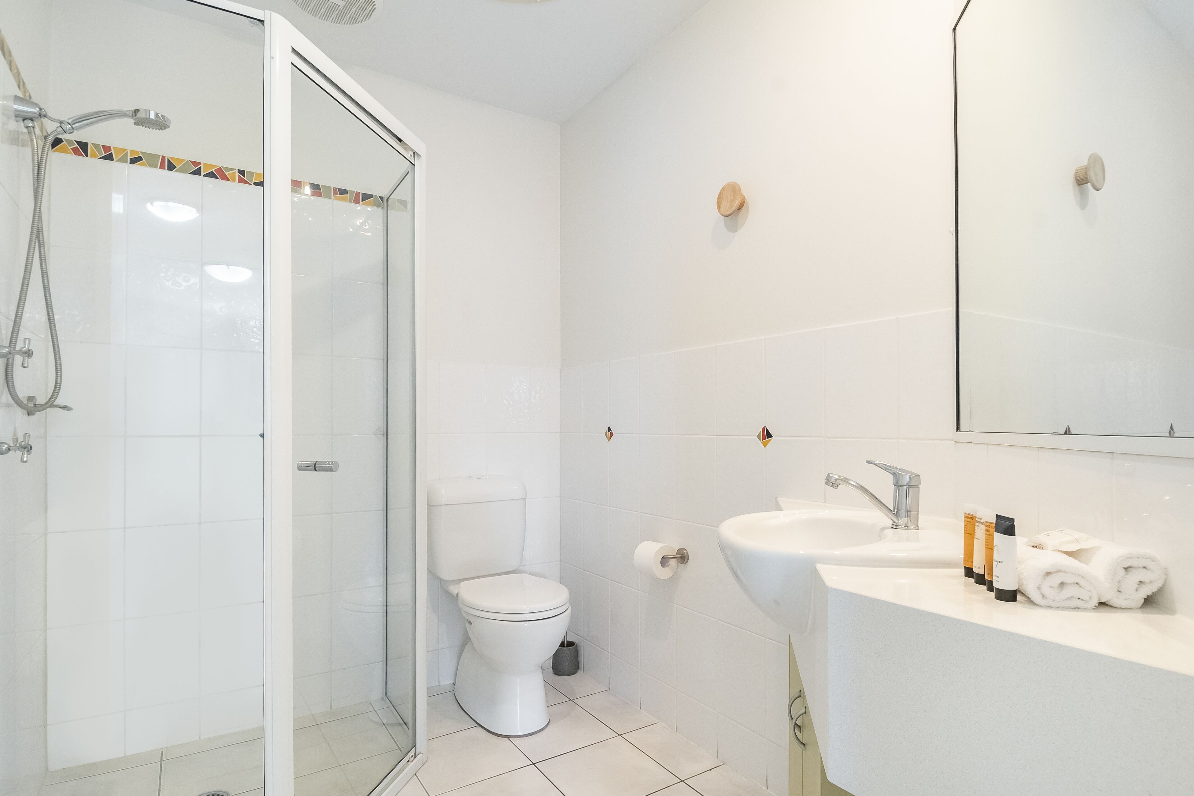 Une salle de bain avec une douche à parois de verre, des toilettes, un lavabo et un miroir.