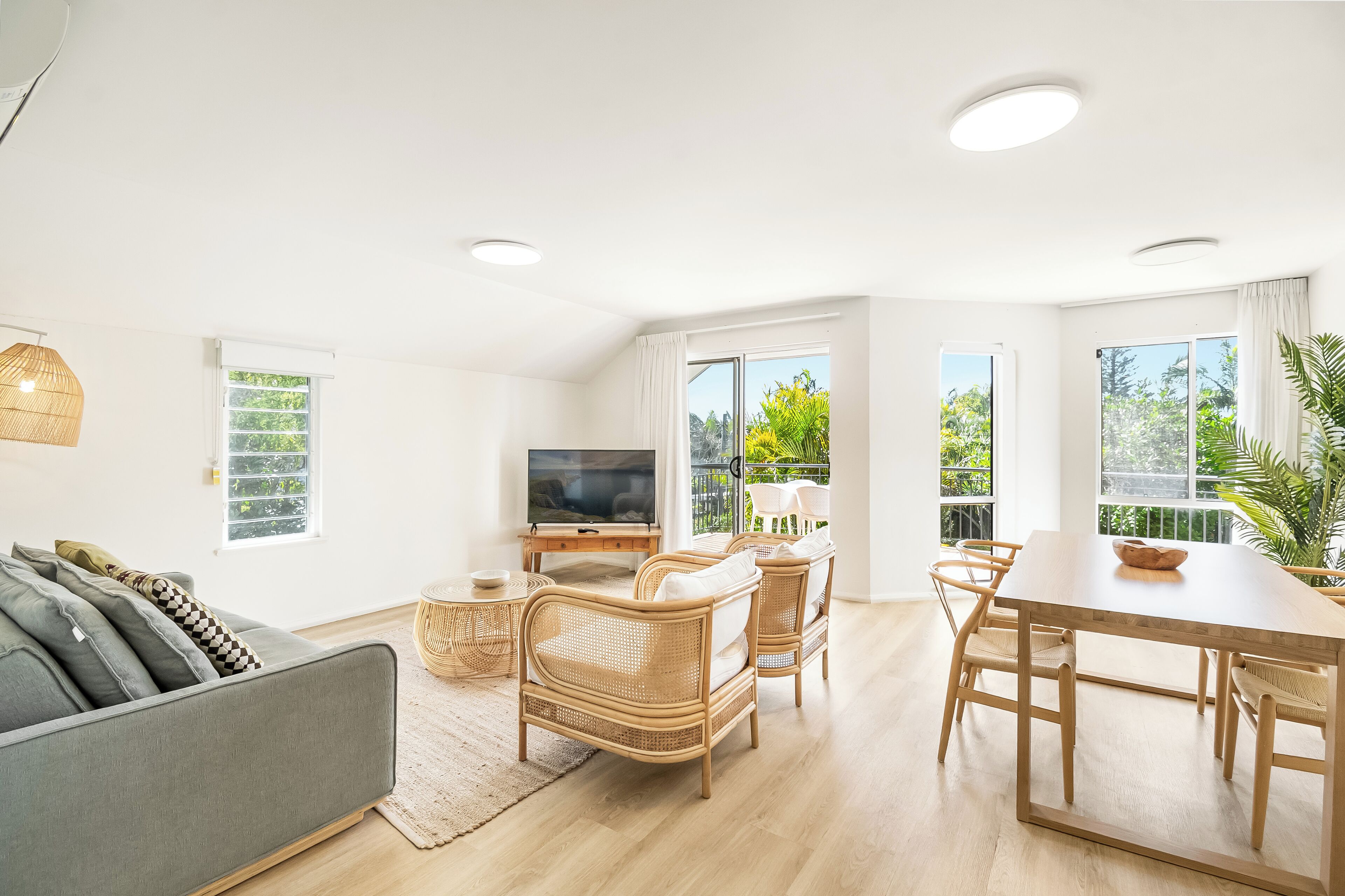 A modern living room with a sofa, TV, dining table, and chairs.