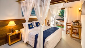 Quarto com cama, mesa de cabeceira, abajur, cadeira e uma pequena mesa com uma planta.