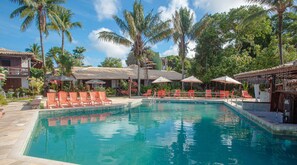 A pool area with lounge chairs and umbrellas, surrounded by palm trees and a clear sky. - Hotel Solar do Imperador (Porto Seguro)