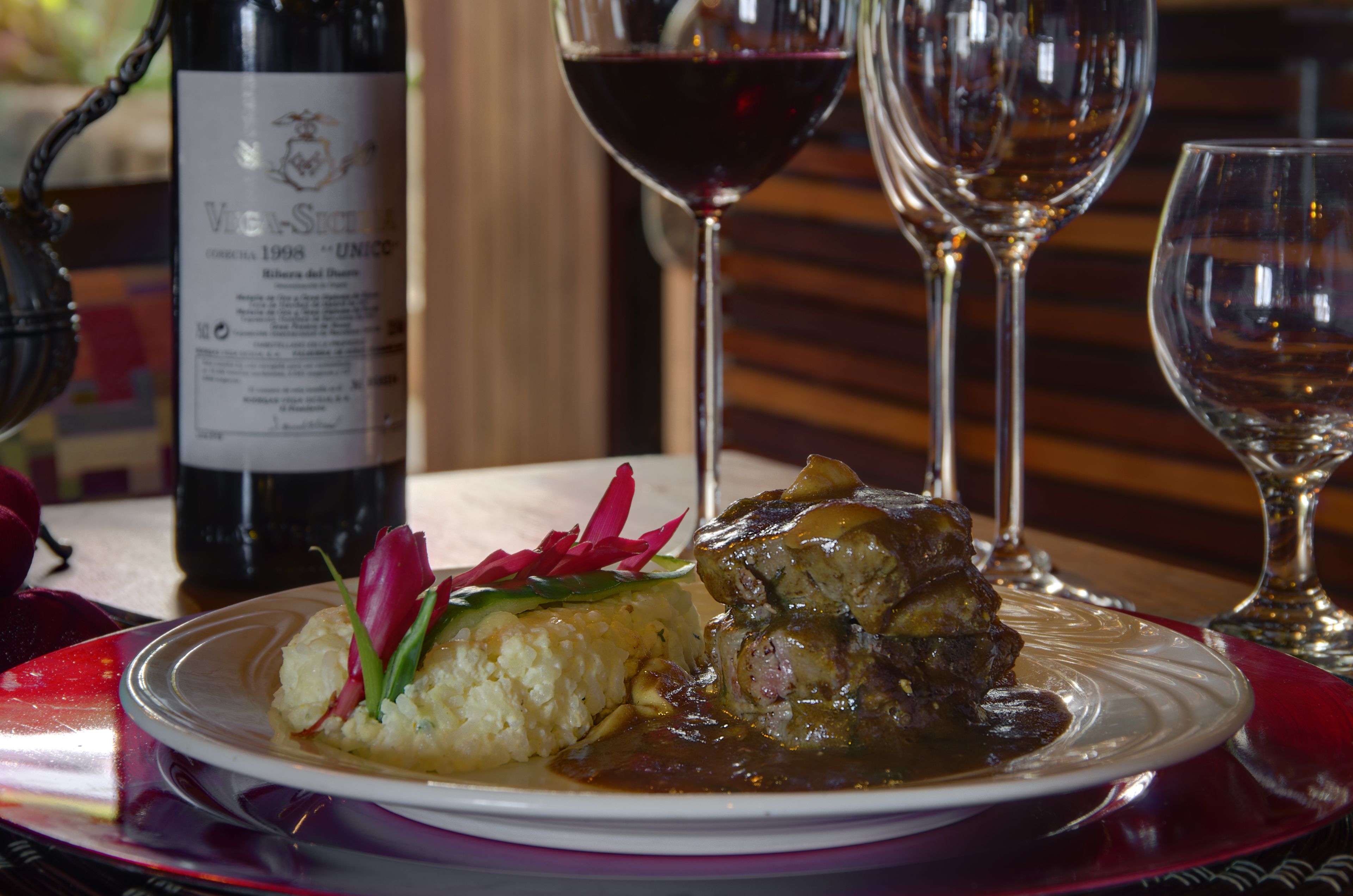 A plate of food with a bottle of wine and glasses on a table.
