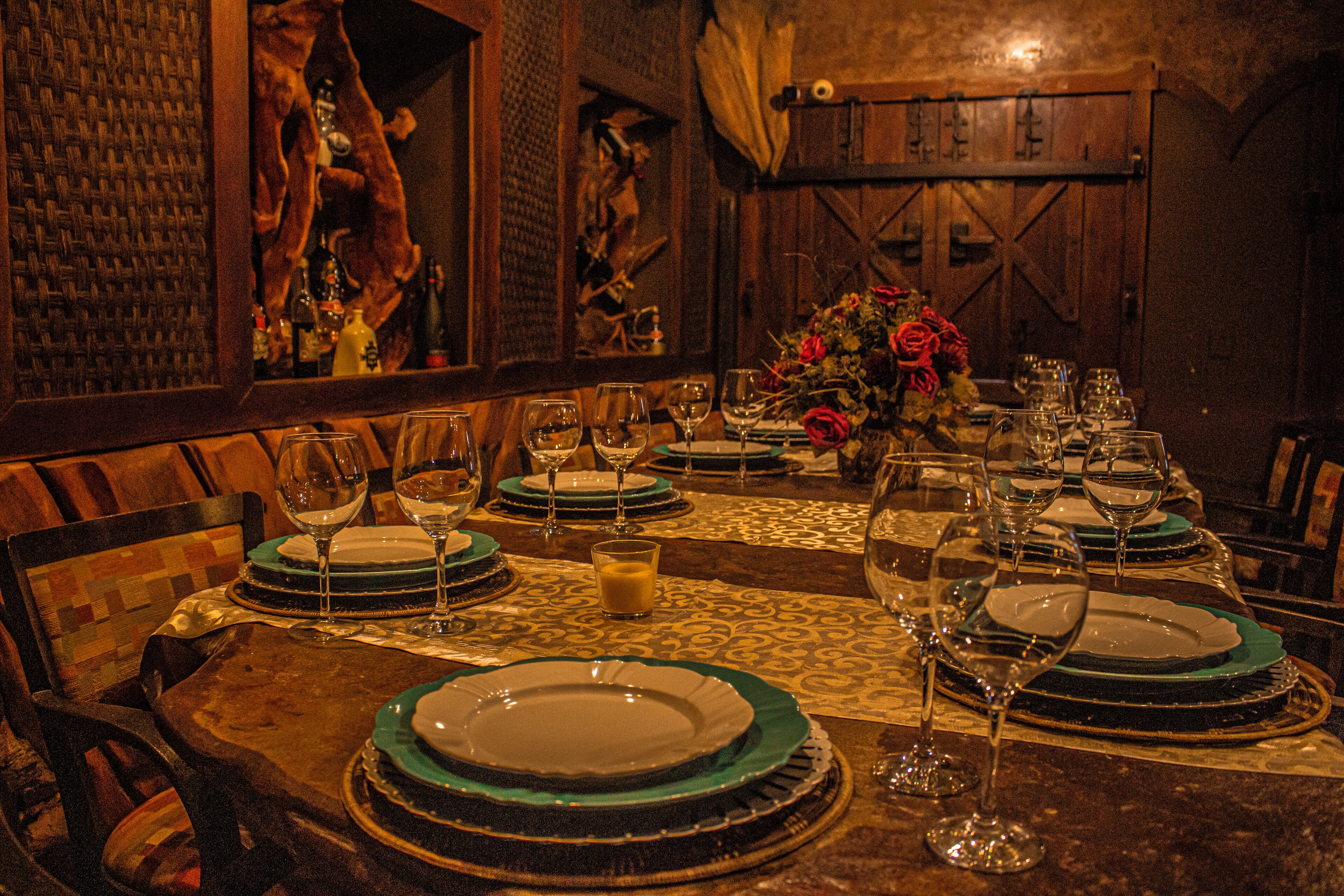 A dining table set with multiple plates, glasses, and a vase of flowers.