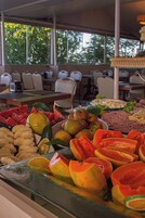 Buffet com frutas e legumes variados, incluindo melancia, maçãs e laranjas.
