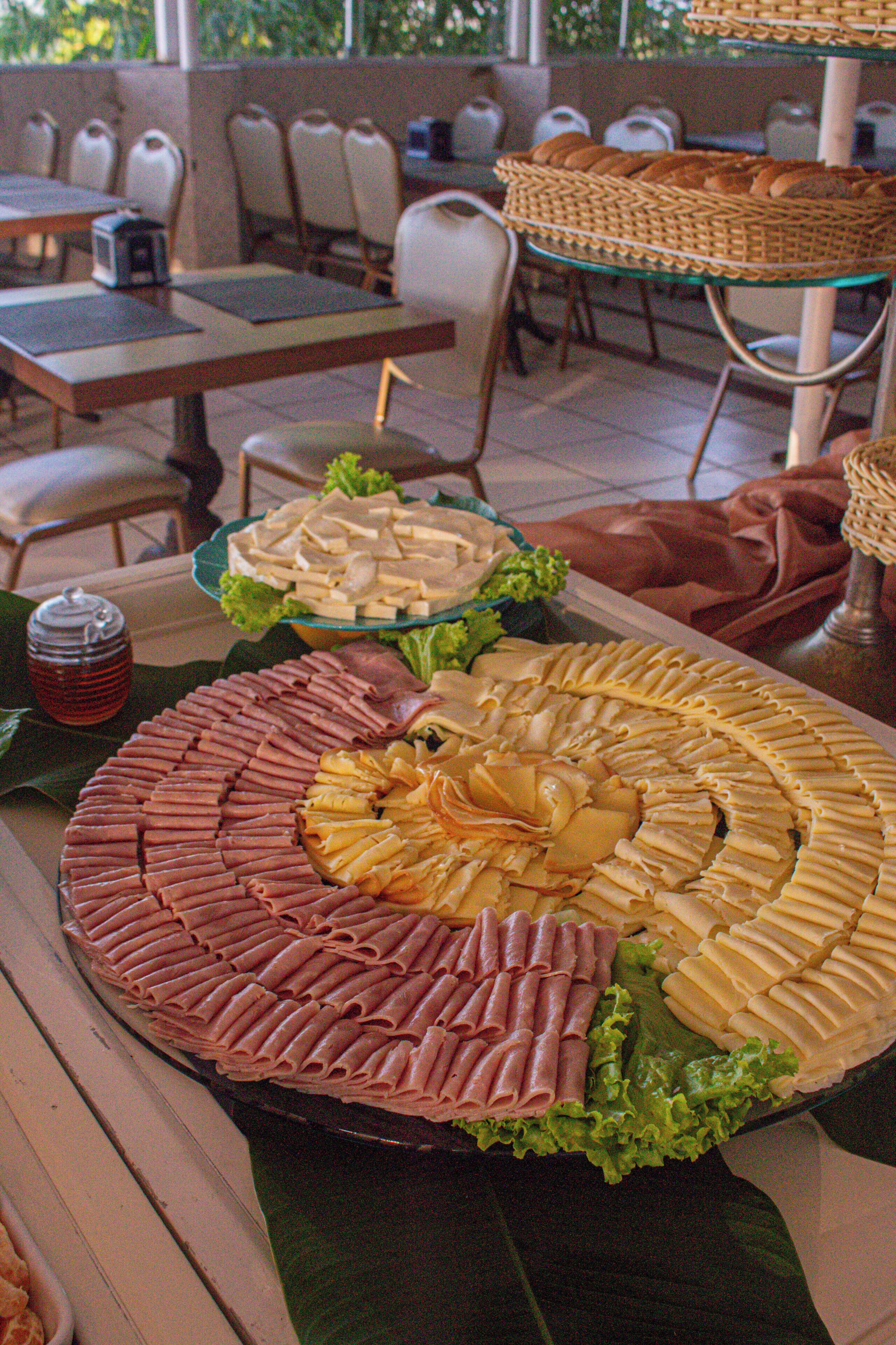 A buffet table with various food items, including meats and cheeses, arranged on a large platter.