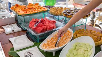 A buffet with various food items including watermelon, oranges, and other fruits.