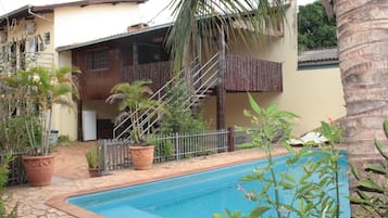 Una piscina al aire libre, sillones reclinables de piscina