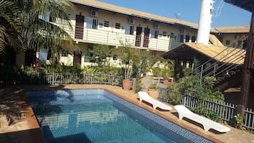 Una piscina al aire libre, sillones reclinables de piscina