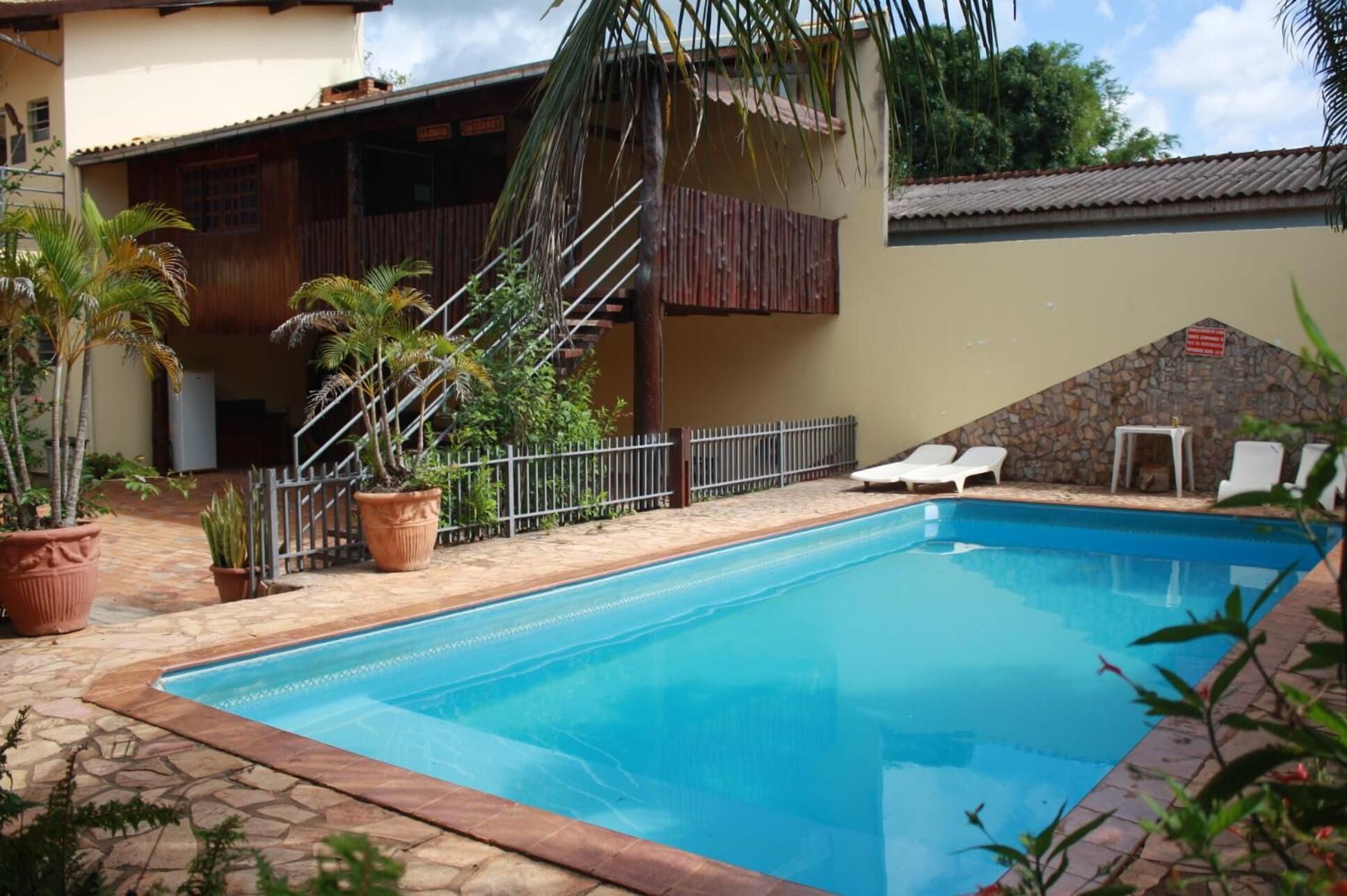 A swimming pool with a stone border, surrounded by potted plants and a stone wall.