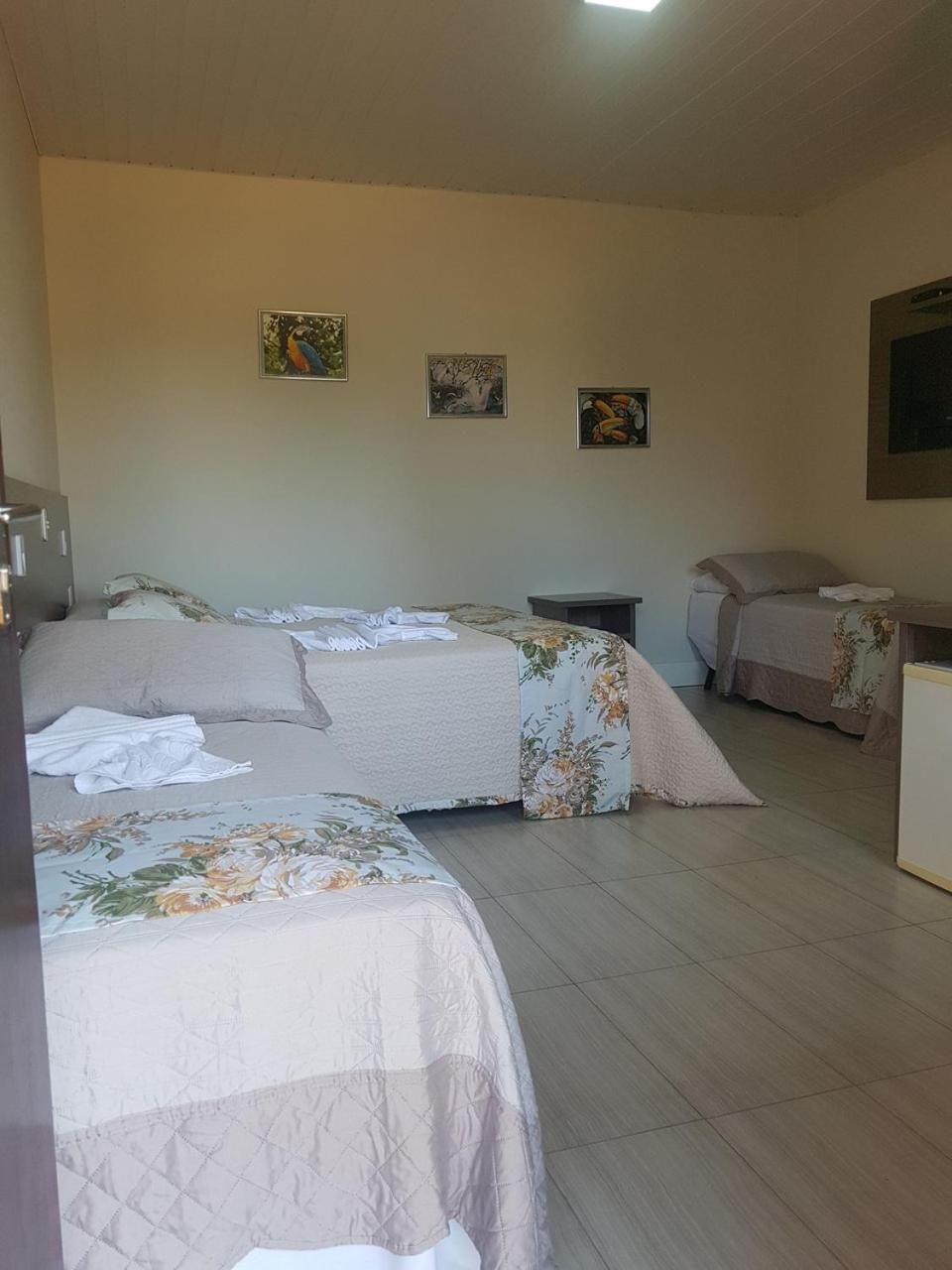 Une chambre d’hôtel avec deux lits, une petite table et un téléviseur fixé au mur.