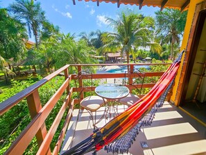 A balcony with a glass table and chairs, a hammock, and a view of a pool and tropical vegetation. - Hotel Pousada Aguas de Bonito (Bonito)