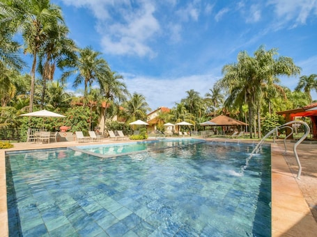 Una piscina techada, una piscina al aire libre, sombrillas