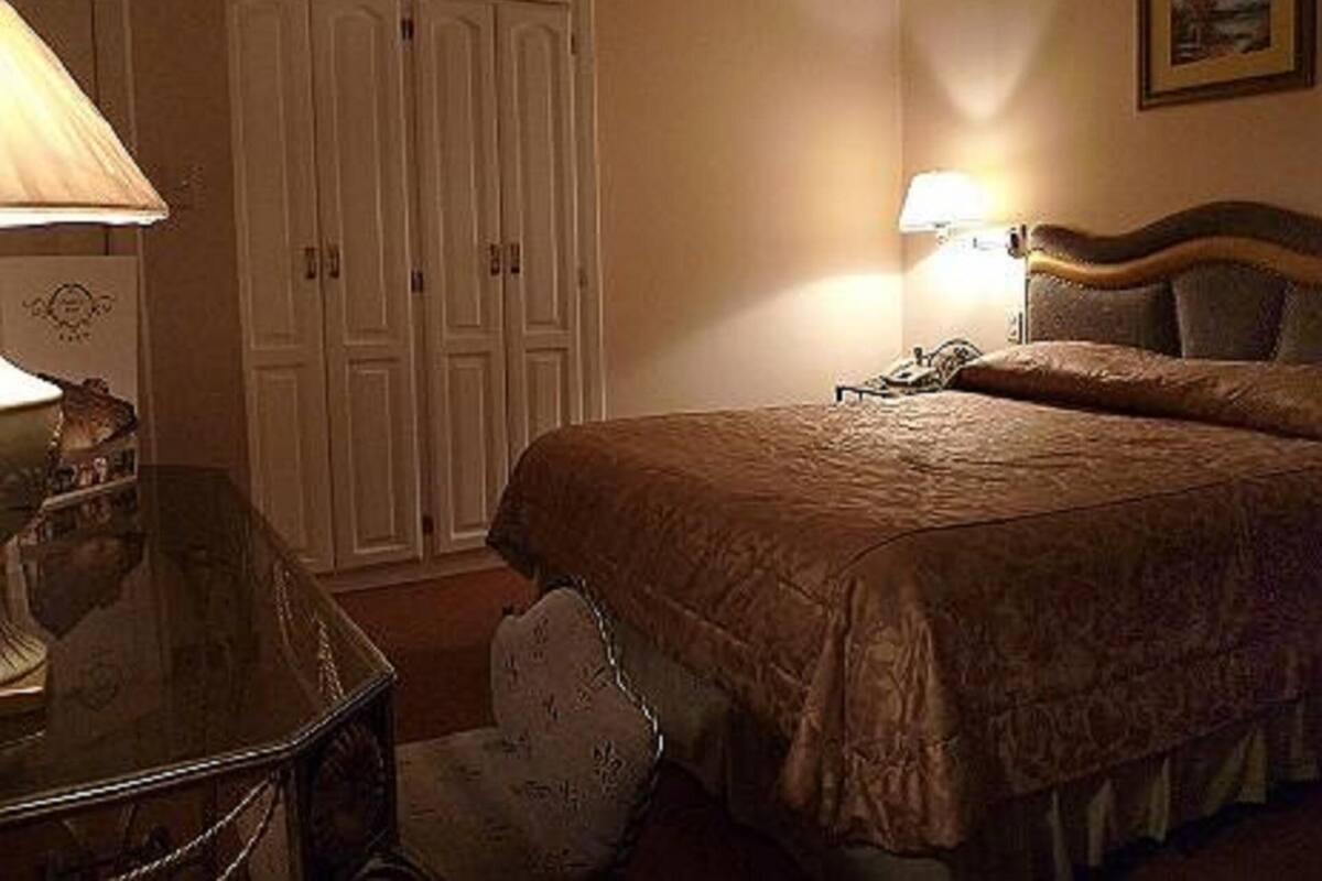 A bedroom with a bed, a nightstand, a lamp, a chair, and a wardrobe.