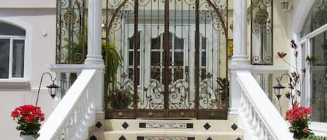 A set of ornate, white-tiled stairs leading to a gated entrance with decorative ironwork.