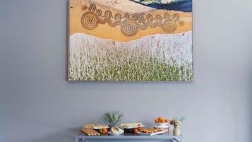 Un mur orné d’un grand tableau représentant une scène de plage et une table de buffet garnie de divers plats.