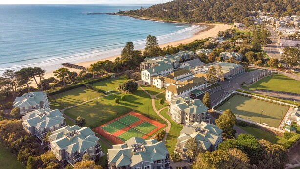 An aerial view of a coastal residential area with houses, a tennis court, and a beach. - Mantra Lorne (Lorne)