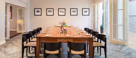 A conference room with a long table set for a meeting, framed pictures on the wall, and a carpeted floor.