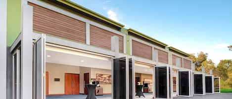 A modern hotel with a glass entrance, wooden paneling, and a paved walkway.
