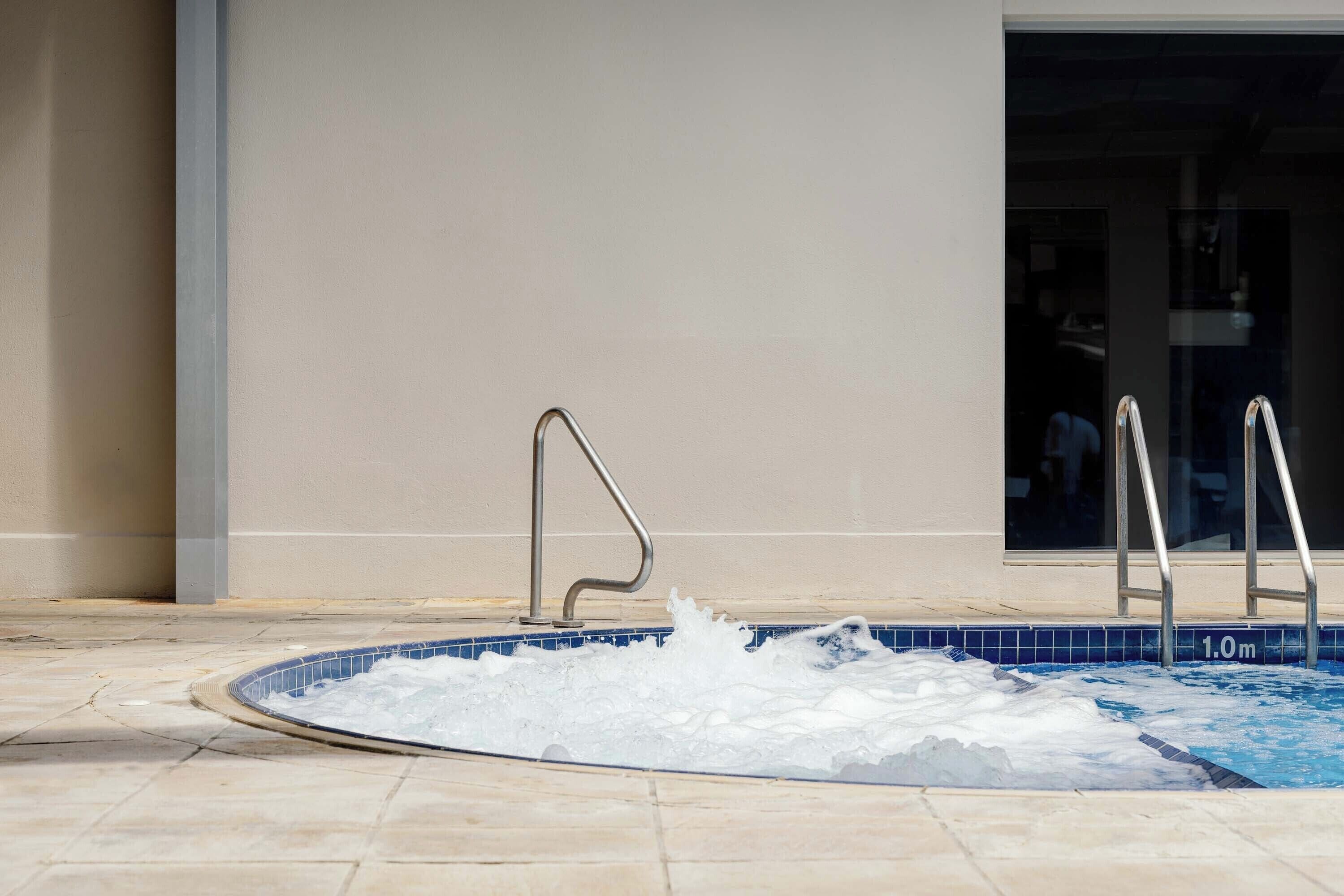 A swimming pool with a tiled edge and metal handrails.