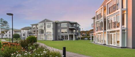 A modern residential building with a well-maintained lawn and a clear sky.