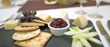 A cheese board with crackers, grapes, and a small bowl of cranberry sauce on a slate board.
