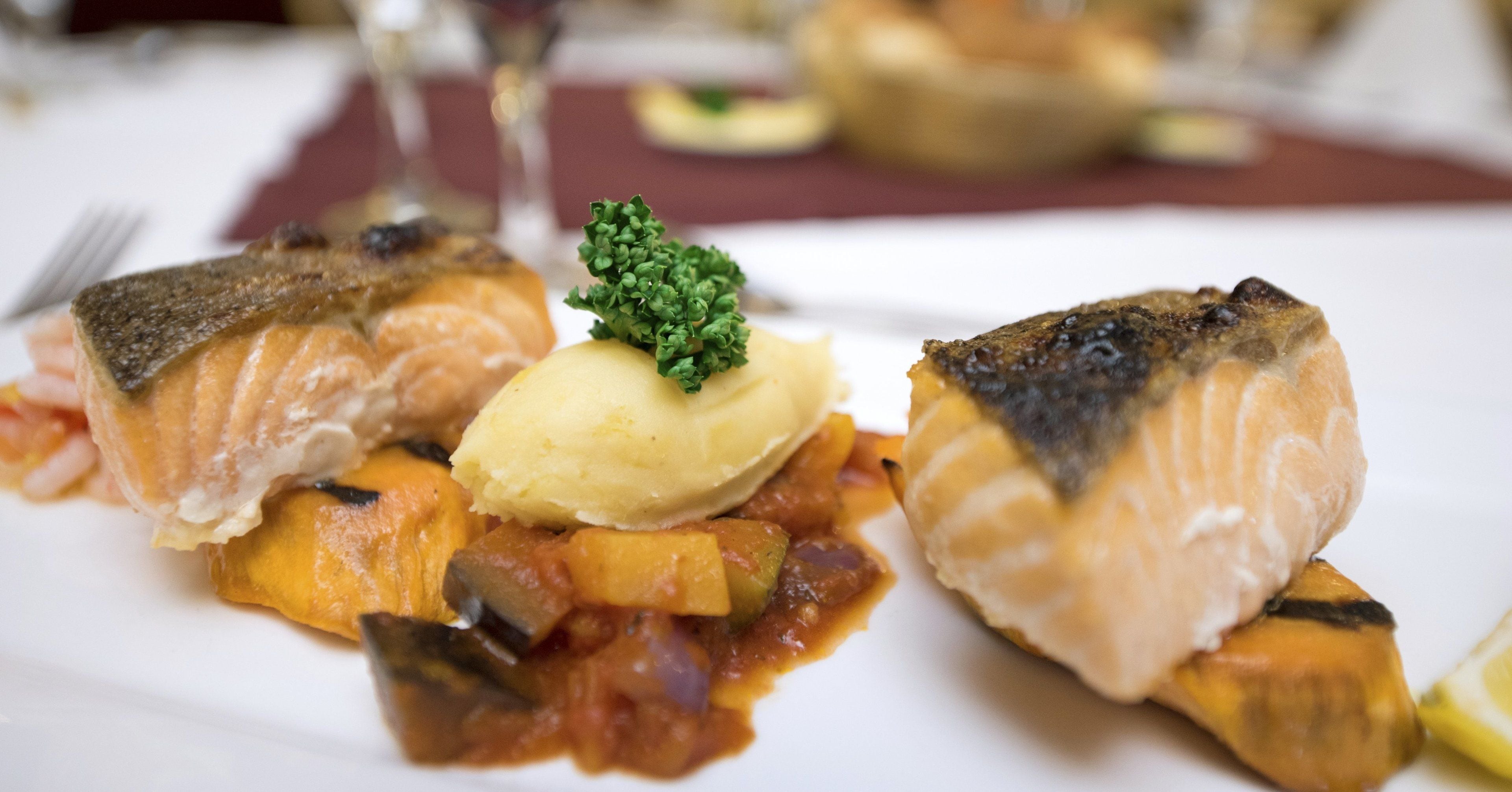 Un plato con salmón, puré de papas y verduras.
